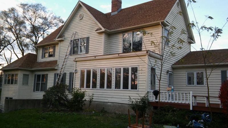 Two-story white house with brown roof and front porch under renovation
