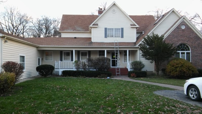 Two-story residential home with white and brick exterior, front porch, and manicured lawn